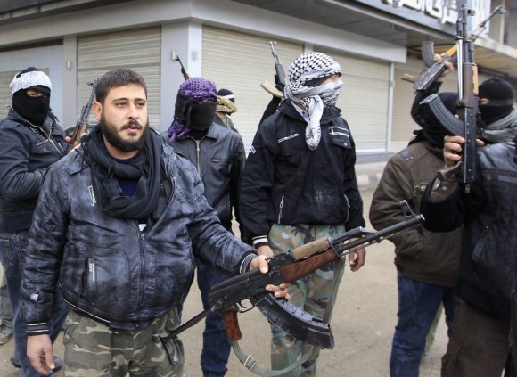 Syrian soldiers, who have defected to join the Free Syrian Army, hold up their rifles as they secure a street in Saqba, in Damascus suburbs